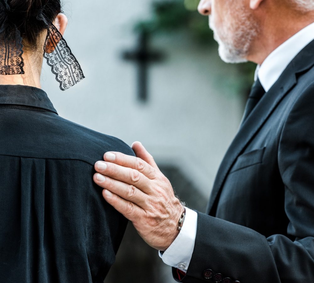 cropped-view-of-man-touching-woman-on-funeral.jpg